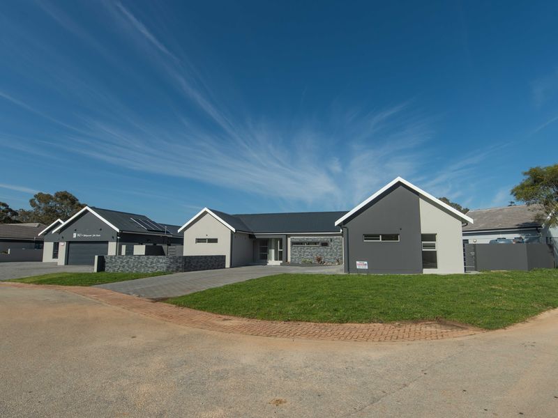 Modern single-story residential house featuring a paved driveway, integrated garage, and contemporary stone and painted facade finishes.