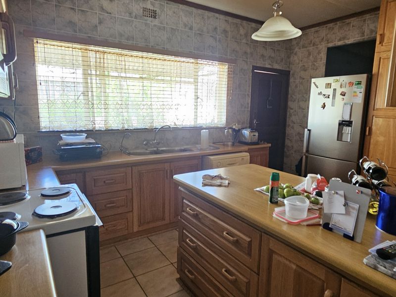A functional kitchen featuring wooden cabinetry, laminate countertops, a central island, and tiled finishes, offering a traditional layout with ample storage space.
