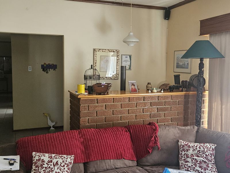 A living room featuring an exposed brick partition wall, timber window pelmet, and neutral wall finishes, offering a traditional layout with potential for modernization.