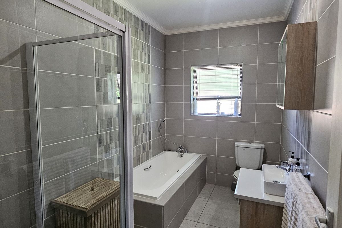 Modern bathroom featuring a tiled shower enclosure, built-in bathtub, vanity with basin, and wall-mounted storage cabinet.