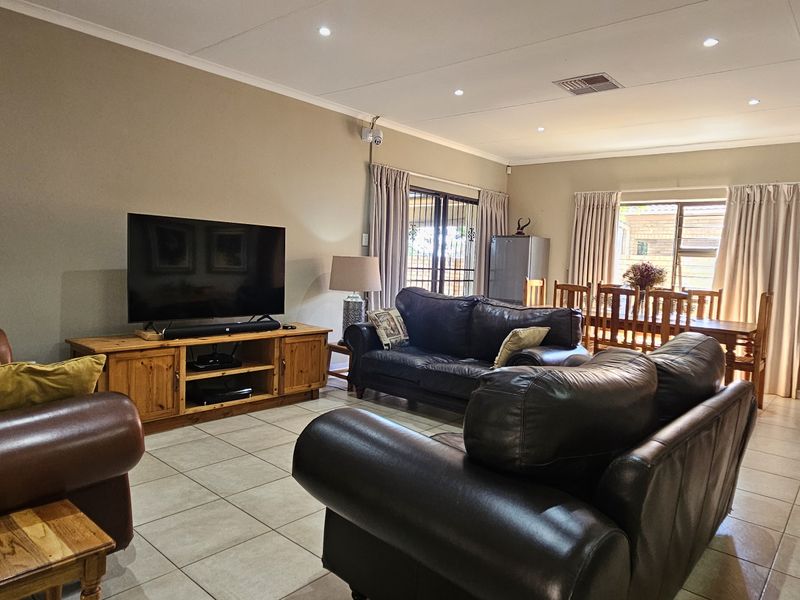 Spacious open-plan living and dining area featuring neutral wall tones, tiled flooring, and recessed lighting with direct access to the outdoor space.