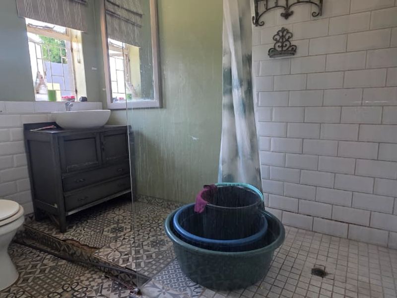 Bathroom featuring subway tile walls, patterned floor tiles, a vanity with vessel sink, and a walk-in shower area with glass screen.