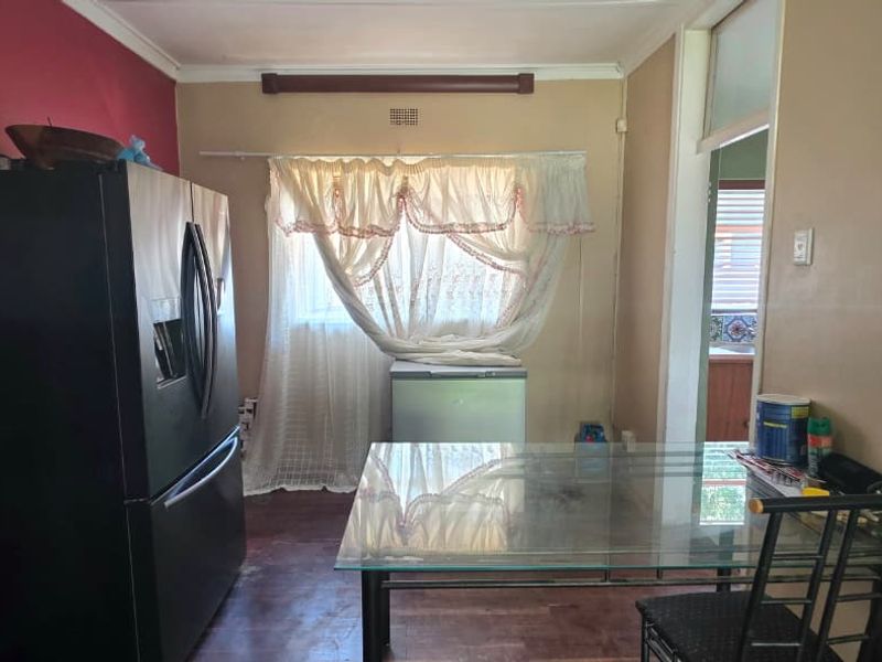 A dining area featuring dated wall finishes and worn flooring, offering potential for modernization and aesthetic improvement.
