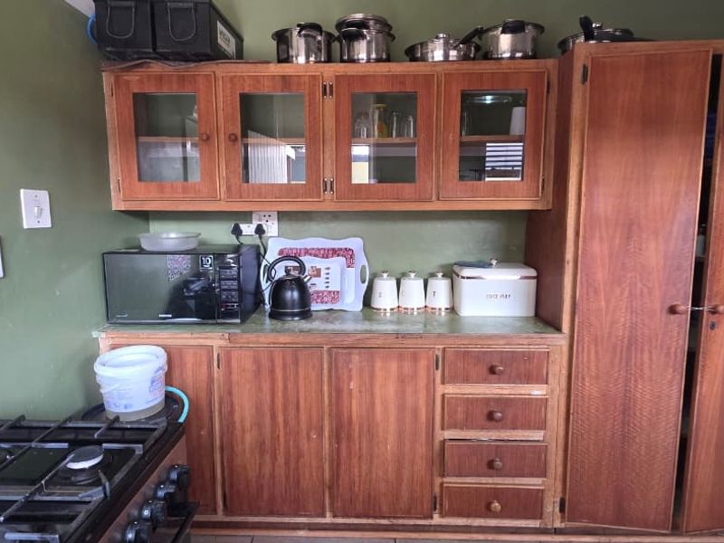 A functional kitchen featuring wooden cabinetry, a gas stove, and decorative tiled splashbacks, offering a dated aesthetic ready for modernization.