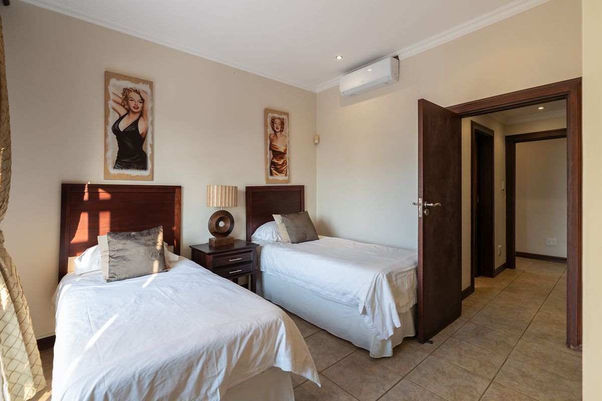A well-maintained bedroom featuring tiled flooring, recessed lighting, and a wall-mounted air conditioning unit, providing a comfortable and functional living space.