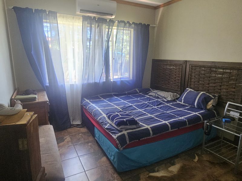 A bedroom featuring tiled flooring and a wall-mounted air conditioning unit.