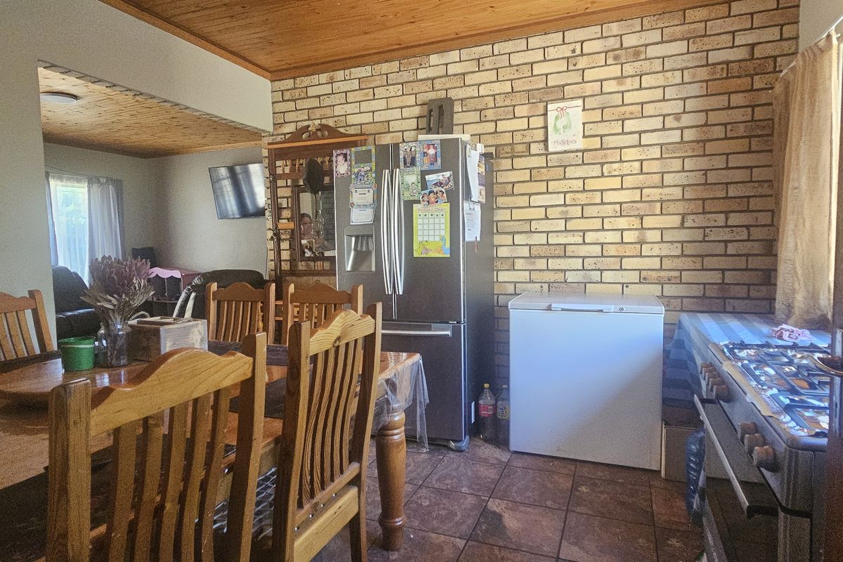 Open plan dining and kitchen area featuring exposed brick walls, timber ceilings, and tiled flooring with a built-in gas stove.