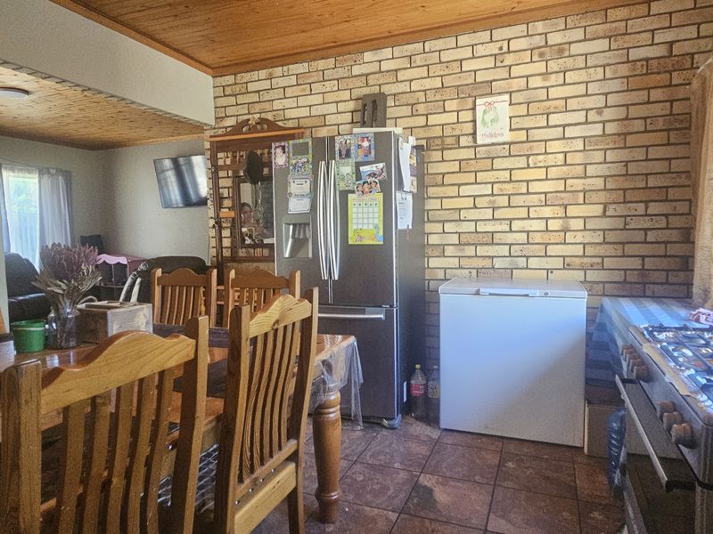 Open plan dining and kitchen area featuring exposed brick walls, timber ceilings, and tiled flooring with a built-in gas stove.