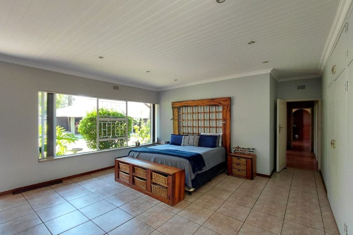 Spacious bedroom featuring tiled flooring, built-in cupboards, and a large window providing ample natural light.