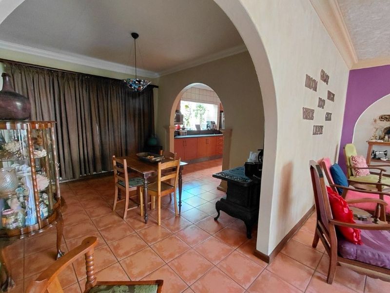 Open plan living and dining area featuring terracotta floor tiles, an arched transition to the kitchen, and coved ceiling details.