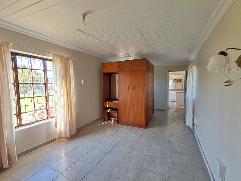 A bedroom featuring tiled flooring, a built-in wardrobe, and a tongue and groove ceiling, with security bars on the window.