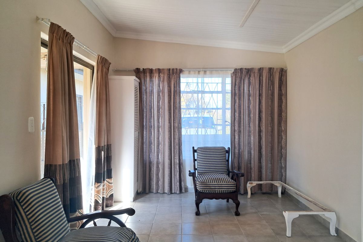 A living room featuring tiled flooring, a coved ceiling, and a sliding glass door providing access to the exterior.