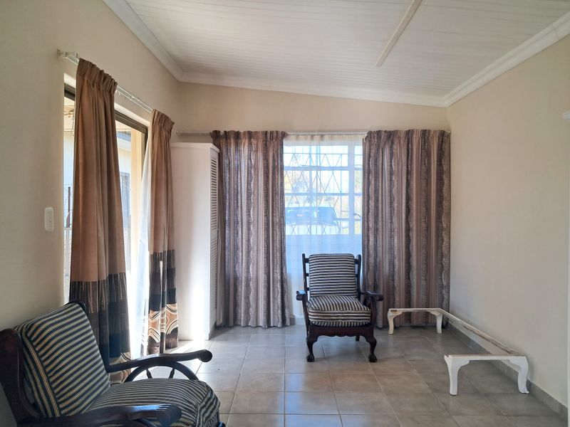 A living room featuring tiled flooring, a coved ceiling, and a sliding glass door providing access to the exterior.