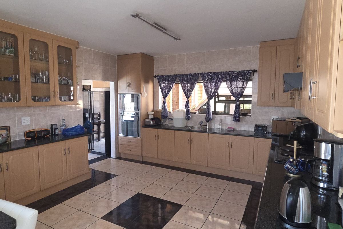 Spacious kitchen featuring light wood cabinetry, granite countertops, tiled flooring, and a built-in oven, offering ample storage and workspace.