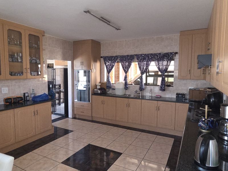 Spacious kitchen featuring light wood cabinetry, granite countertops, tiled flooring, and a built-in oven, offering ample storage and workspace.