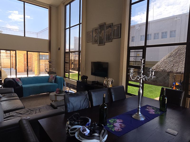 Spacious open-plan living and dining area featuring double-volume windows that provide abundant natural light and views of the rear garden.