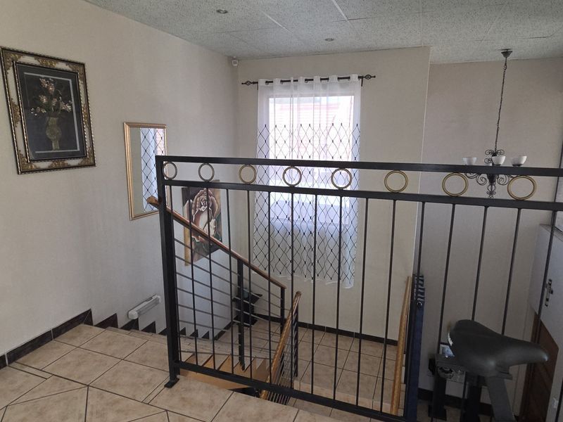 A landing area featuring tiled flooring and a decorative wrought iron balustrade overlooking the staircase.