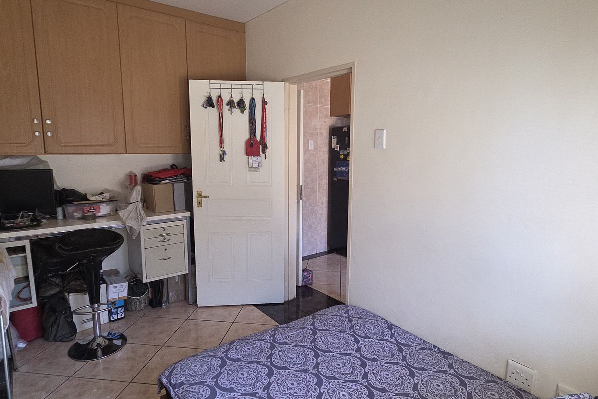 A bedroom featuring tiled flooring and built-in cabinetry, with an adjoining room visible through the doorway.