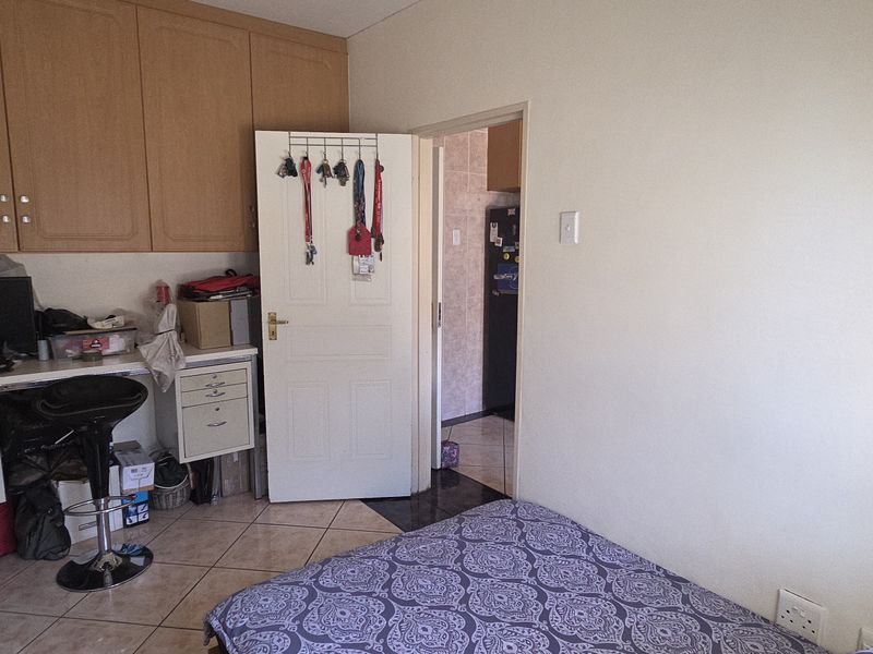 A bedroom featuring tiled flooring and built-in cabinetry, with an adjoining room visible through the doorway.