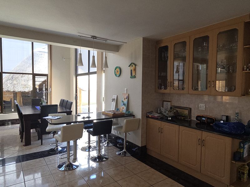 Spacious open-plan living and dining area featuring tiled floors, large windows for natural light, and built-in kitchen cabinetry with granite countertops.