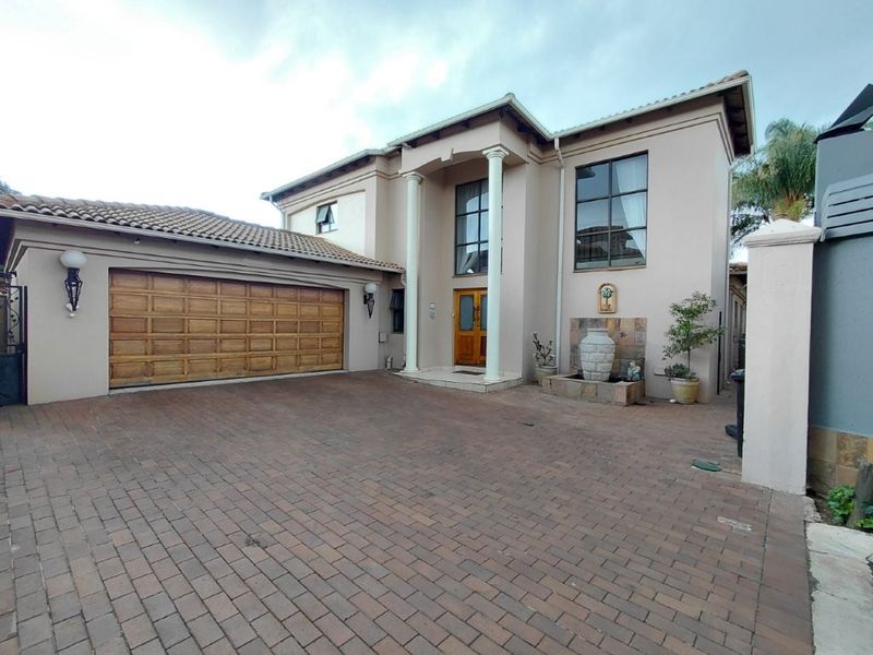Front elevation of a double-story house featuring a paved driveway, double garage, and a covered entrance with decorative columns.