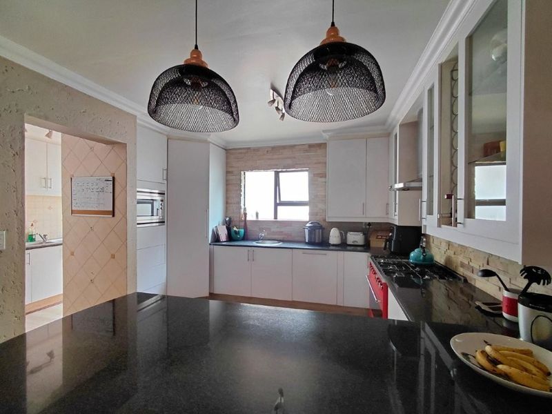 Modern kitchen featuring granite countertops, built-in cabinetry, gas hob, and integrated appliances, with a convenient adjacent scullery area.