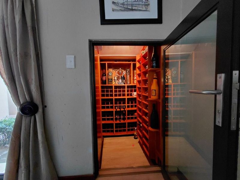 A dedicated walk-in wine cellar featuring custom built-in timber wine racking and a glass entry door.