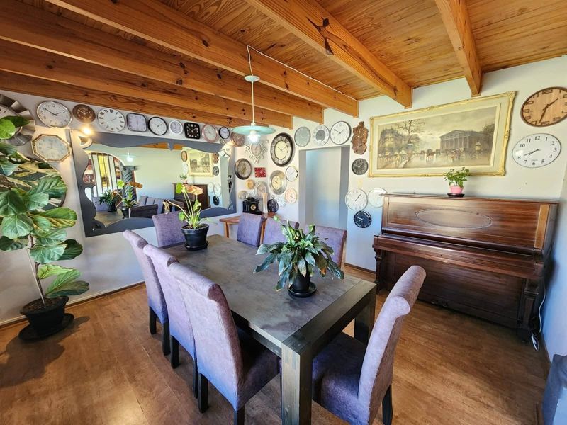 Dining room featuring exposed timber beam ceilings and laminate flooring, providing a rustic aesthetic with a large wall mirror.