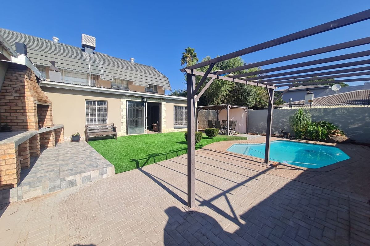 Rear garden featuring a swimming pool, paved patio area, pergola, and a built-in brick braai, perfect for outdoor entertaining.