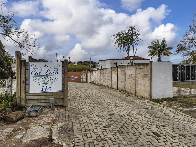 Entrance view of Cal-Eath Gardens featuring a paved driveway, secure metal gate, and precast concrete boundary walling.