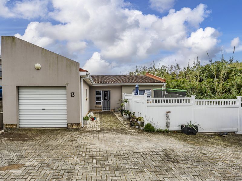 Front exterior view of a townhouse featuring a single garage, paved driveway, and white vinyl fencing.