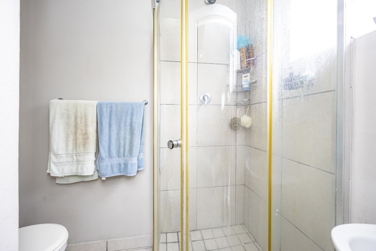 A functional bathroom featuring a shower enclosure with tiled walls and flooring, providing essential amenities for the townhouse.