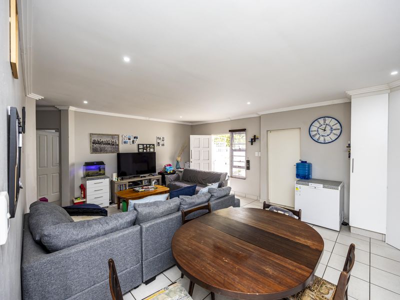 Open-plan living and dining area featuring tiled flooring, recessed downlighting, and neutral wall finishes, providing a functional and connected space.