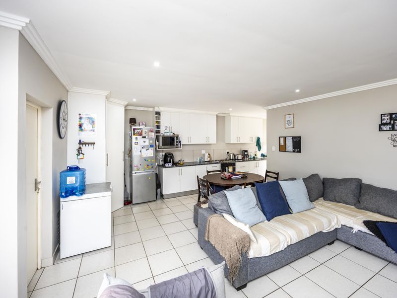 Open-plan living and kitchen area featuring tiled flooring, white cabinetry, and recessed lighting, creating a functional and connected space for daily living.