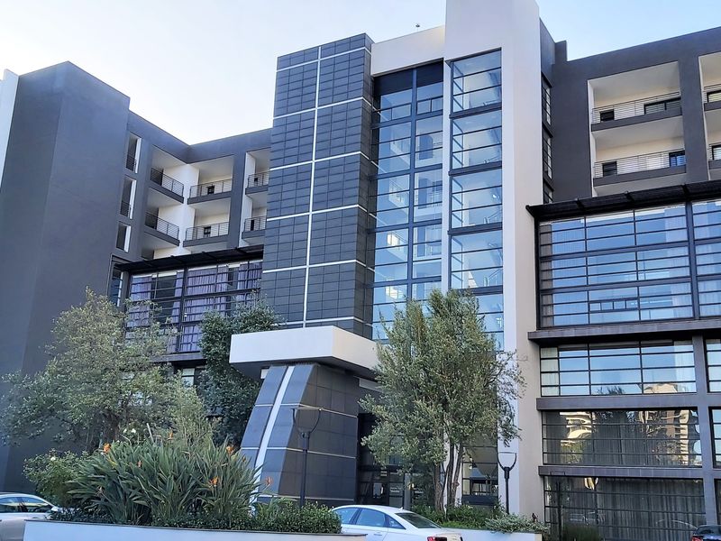 A modern multi-story apartment building featuring a contemporary facade with glass curtain walls, tiled cladding, and private balconies.