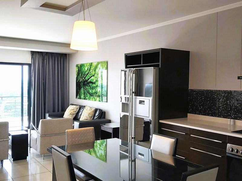 Modern open-plan living area featuring a sleek kitchen with built-in appliances, mosaic backsplash, and seamless access to a private balcony.
