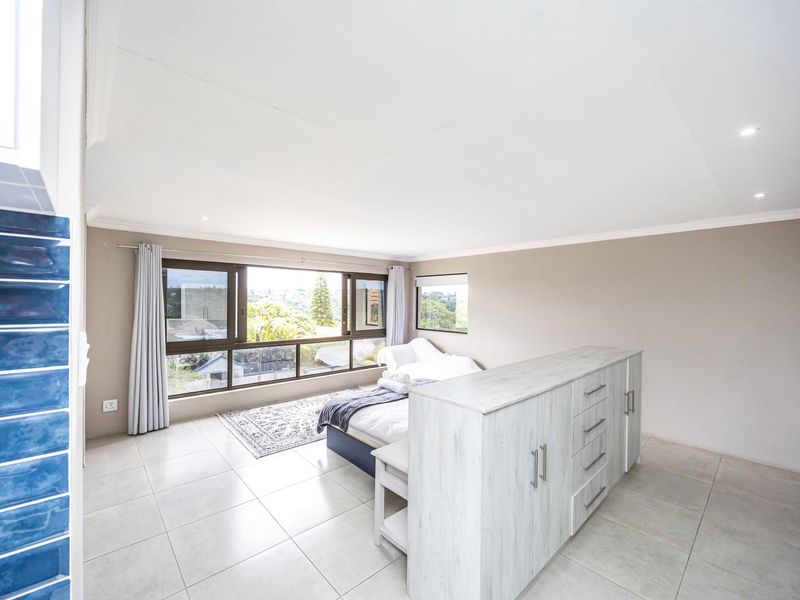 Spacious bedroom featuring large windows with natural light, neutral tiled flooring, recessed lighting, and built-in storage cabinetry.