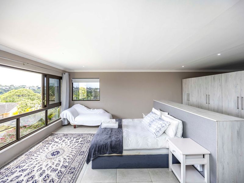 Spacious bedroom featuring large windows with scenic views, built-in cupboards, and neutral tiled flooring.