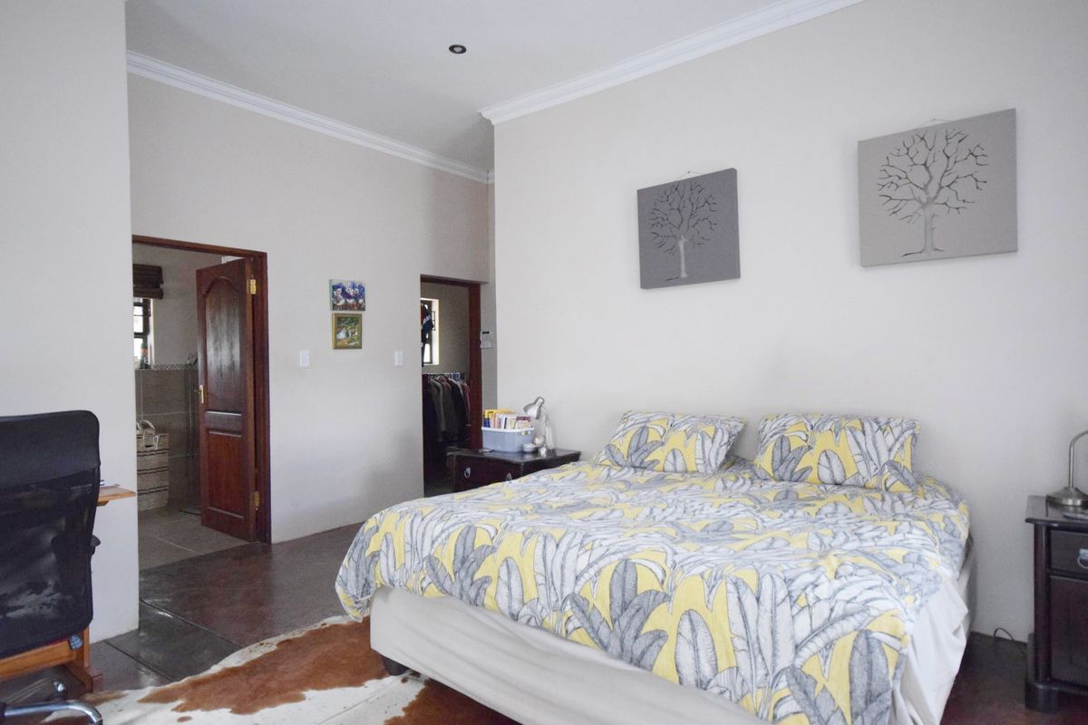 A spacious bedroom featuring neutral walls, coving, recessed lighting, and tiled flooring, with direct access to an en-suite bathroom and walk-in closet.