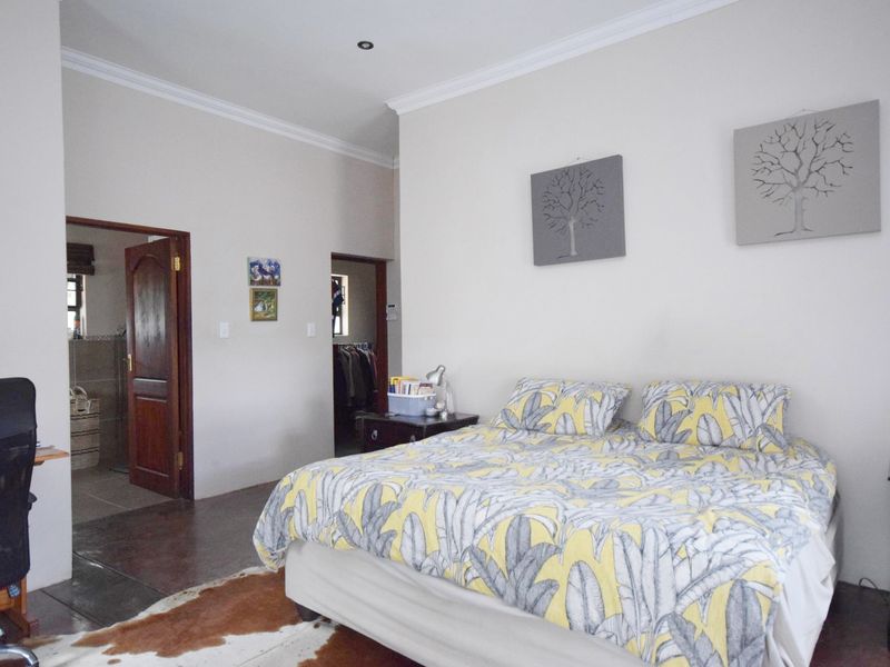 A spacious bedroom featuring neutral walls, coving, recessed lighting, and tiled flooring, with direct access to an en-suite bathroom and walk-in closet.
