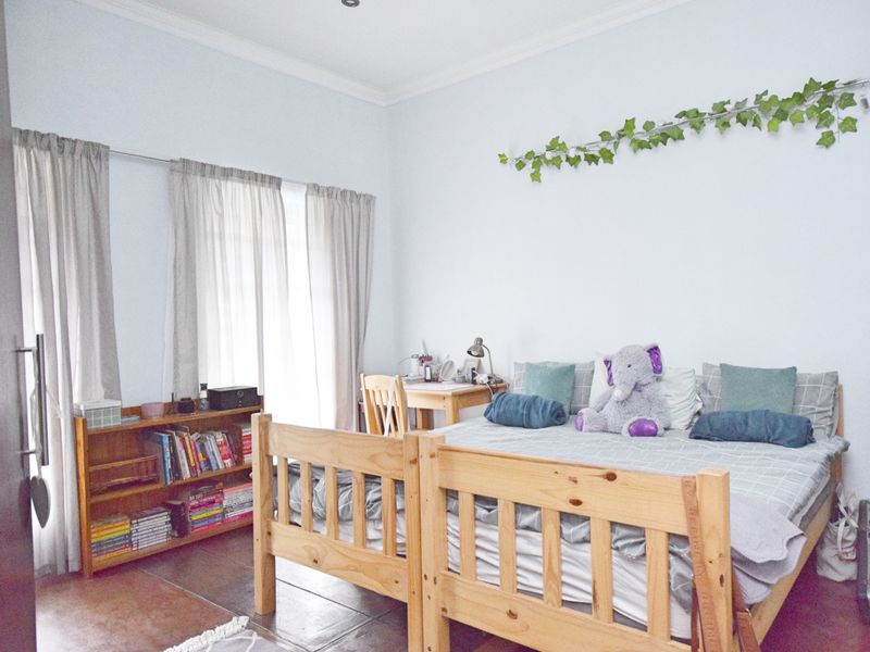 A bedroom featuring tiled flooring, recessed downlighting, and large windows with curtain rails, offering a functional and well-lit living space.