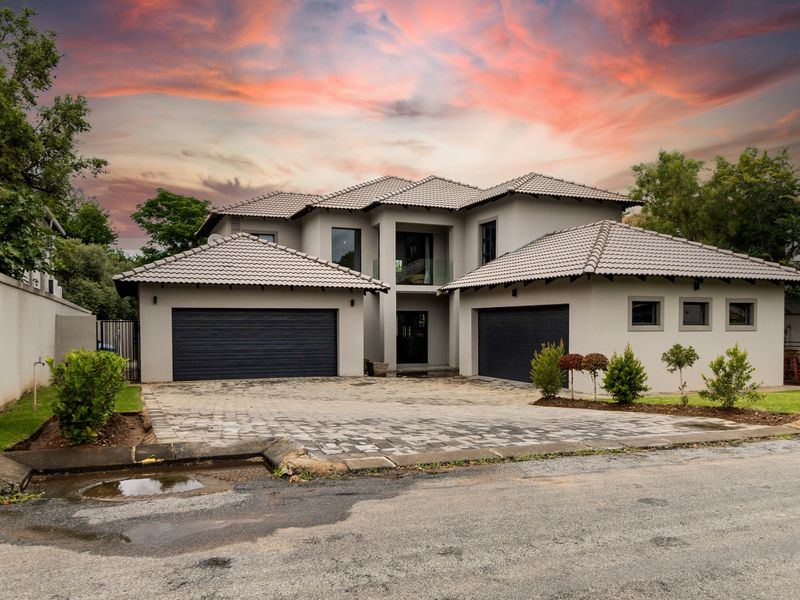 Modern double-story residence featuring a paved driveway, double garage, and contemporary architectural design with a tiled roof.