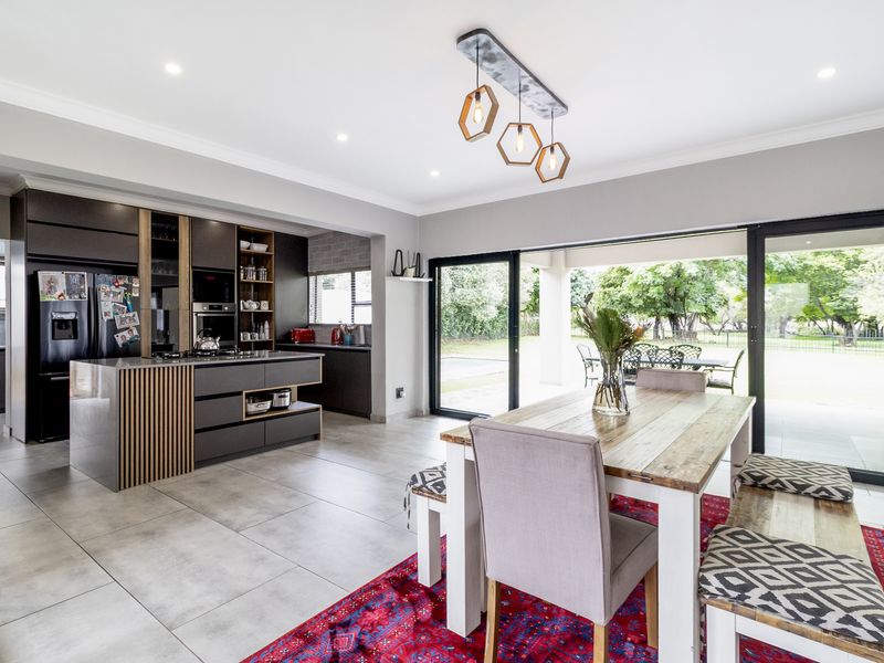 Modern open-plan kitchen and dining area featuring sleek cabinetry, a central island, and large sliding doors opening to the outdoor patio.