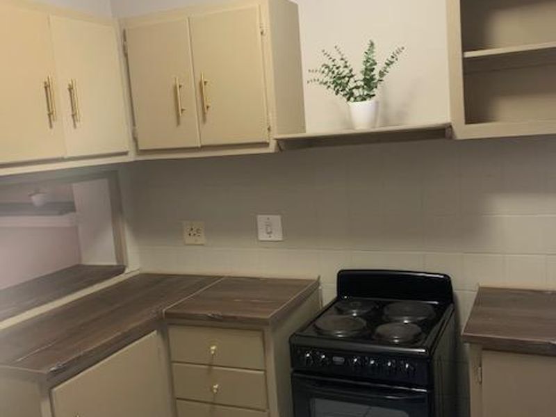 A functional kitchen featuring built-in cabinetry, laminate countertops, a tiled backsplash, and a freestanding electric stove with a classic layout.