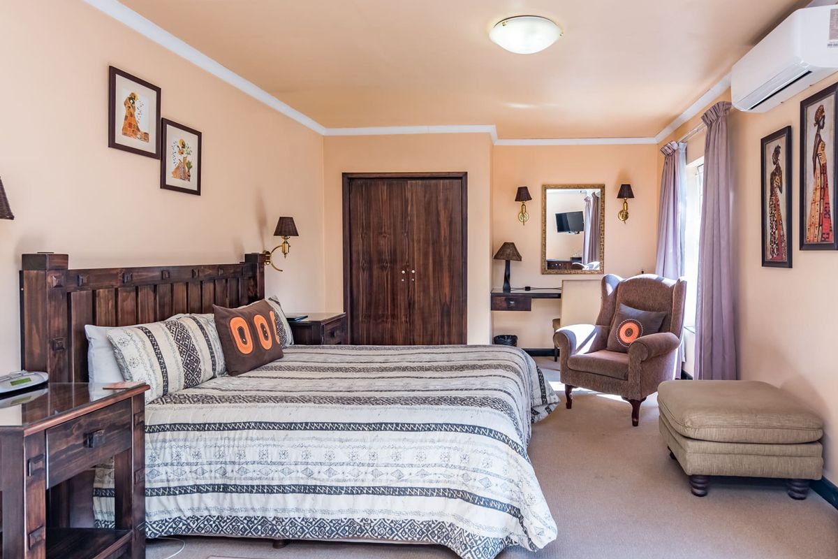 A well-maintained bedroom featuring built-in wooden wardrobes, wall-mounted air conditioning, and neutral carpeting, offering a comfortable and functional living space.
