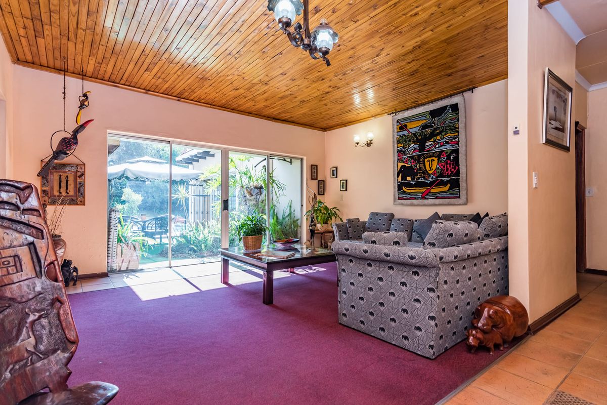 Spacious living room featuring a warm timber-clad ceiling, large sliding glass doors providing natural light, and direct access to the outdoor patio area.