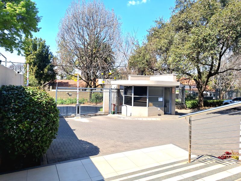 The property entrance features a secure guard house, automated vehicle gate, and paved driveway, providing controlled access and enhanced security for the apartment complex.