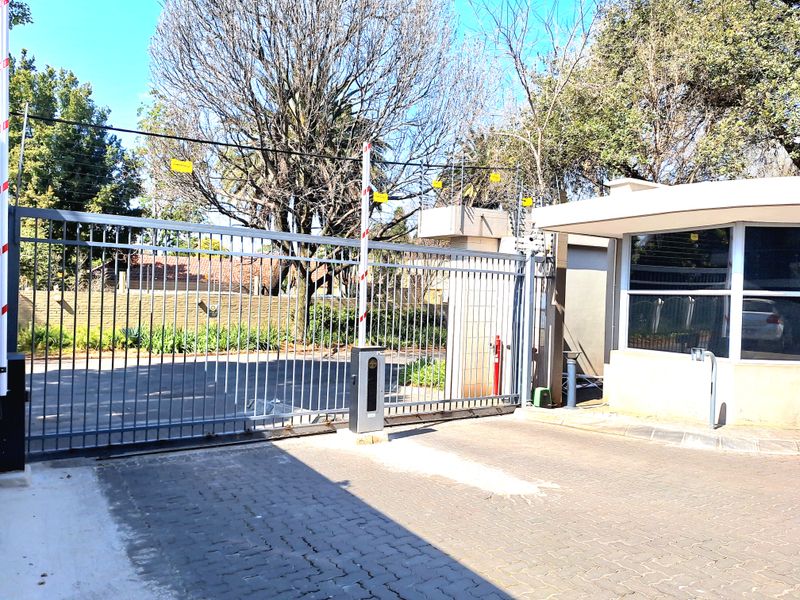 Secure apartment complex entrance featuring an automated sliding gate, boom barrier, and electric fencing for enhanced property security.