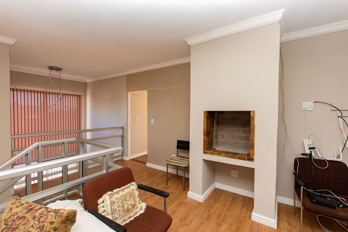 Living area featuring a built-in fireplace, laminate flooring, and crown molding, with an open staircase railing overlooking the lower level.