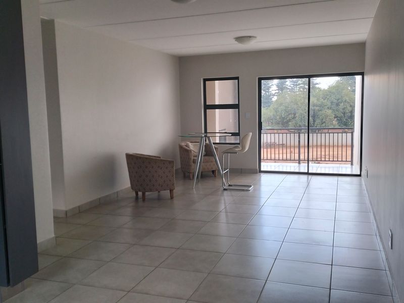 Spacious open-plan living area featuring neutral tiled flooring and large sliding glass doors that provide natural light and direct access to the balcony.